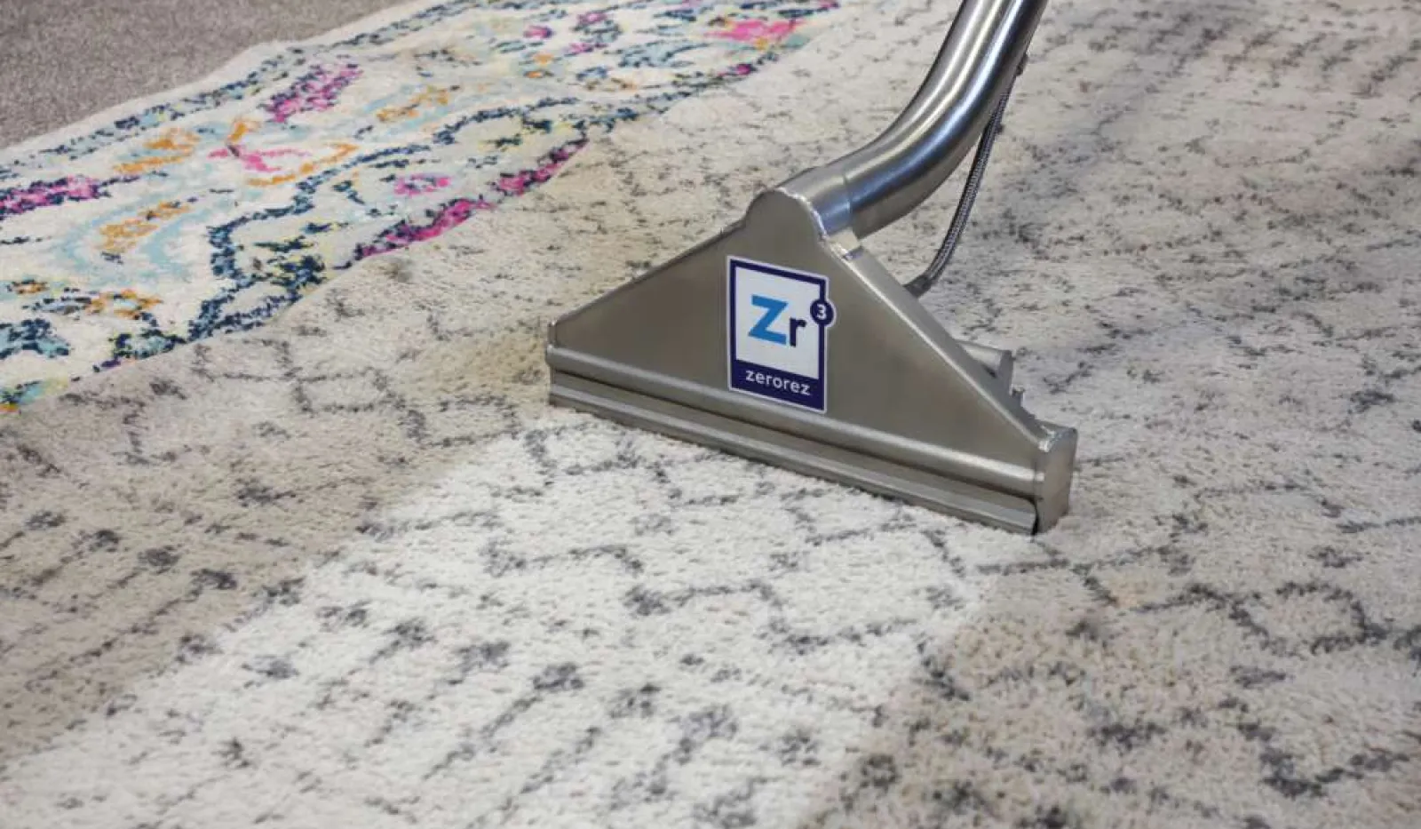 Professional carpet cleaning tool visibly removes dirt, restoring a colorful patterned rug to clean condition.