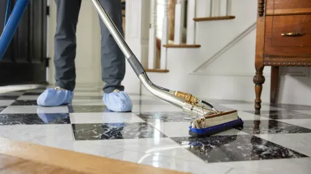 Professional cleaning service using equipment to clean black and white checkered tile floor indoors.