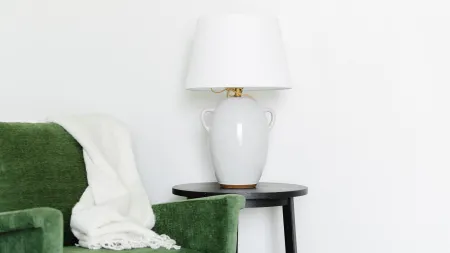 a green chair next to a lamp on white carpet